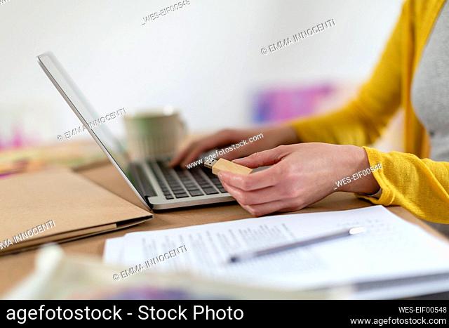 Mid adult woman holding USB stick by laptop on table at home