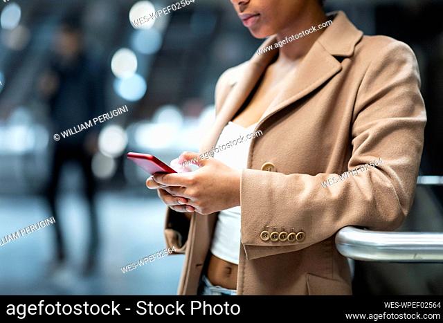 Close-up of young woman using cell phone at subway station