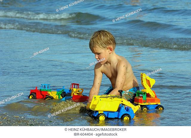 Boy sitting on the beach playing, Caorle, Veneto, Italy