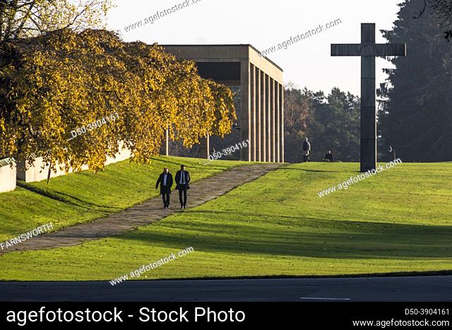 Stockholm, Sweden People on path with cross at the Woodlawn cemetary, or Skogskyrkogarden in the fall