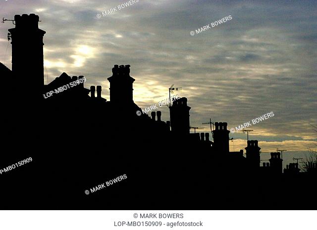 England, City of Brighton and Hove, Hove, Row of chimney pots in silhouette against a grey sky in Hove
