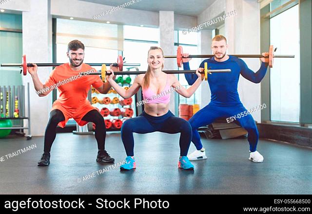 Group of fit young people doing weight exercise in a modern gym