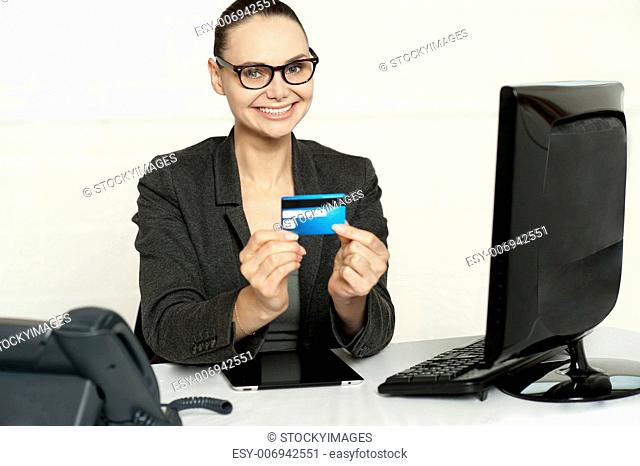 Smiling corporate lady in her office showing credit card to camera