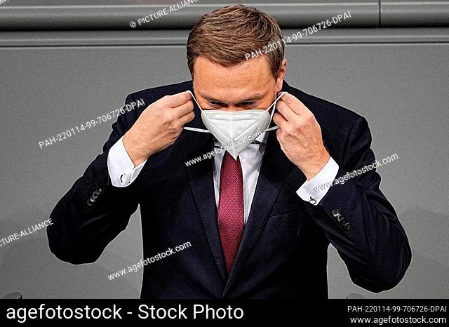 14 January 2022, Berlin: Christian Lindner (FDP), Federal Minister of Finance, puts on his mask in the debate on the policies of the traffic light coalition in...
