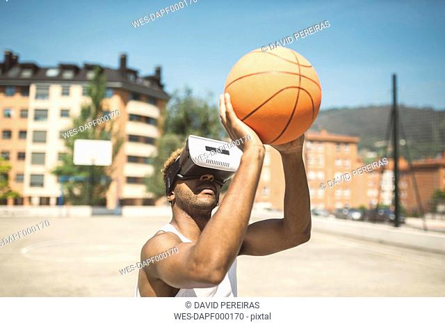 Young man playing basketball with virtual reality glasses on