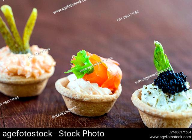 Macro close up of three Mini puff pastry tartlets with seafood filling. Tartlets filled with smoked salmon, cottage cheese, creamy crab and beluga fish caviar