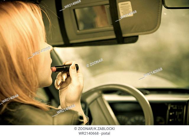girl painting her lips doing make up while driving the car