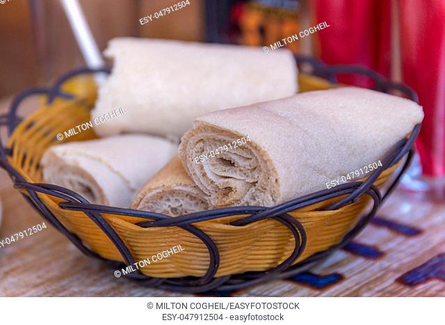 Rolls of Injera in a serving bowl. Injera is a sourdough flatbread made from teff flour. It is the national dish of Ethiopia, Eritrea, Somalia and Djibouti
