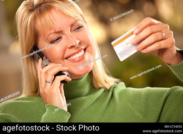 Cheerful smiling woman using her phone with credit card in hand