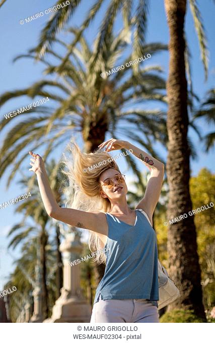 Carefree young woman moving under palm tree