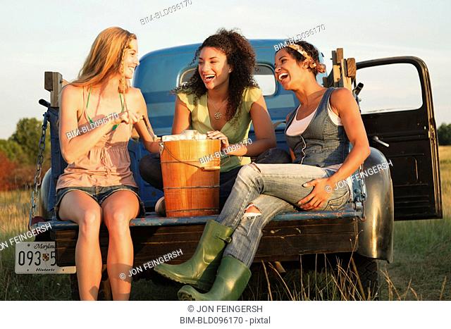 Laughing friends churning ice cream in back of truck