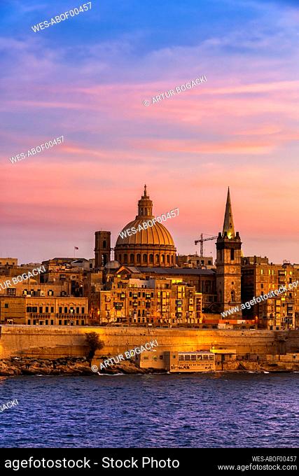 Malta, Valletta, City skyline at sunset, boats in Marsamxett Harbour in foreground