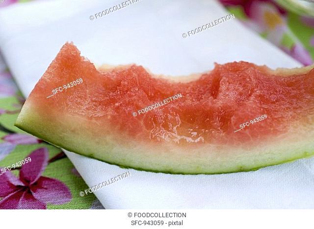Slice of watermelon with bites taken on fabric napkin