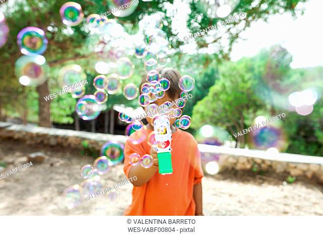 Little boy playing with soap bubble machine