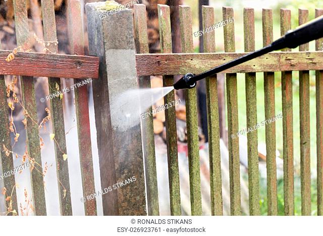cleaning dirty garden fence post with high pressure washer