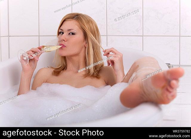 blonde Frau in einer Badewanne mit Champagner