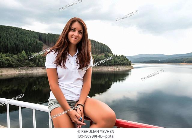 Woman sitting on safety barrier by lake, Koralat, Zagrebacka, Croatia