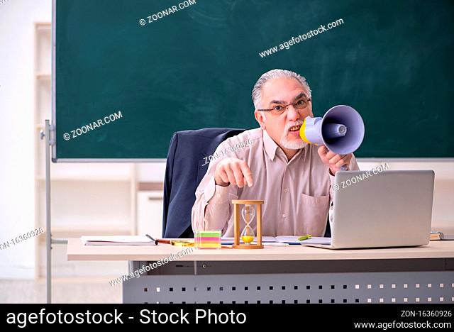 Old male teacher in the classroom of college