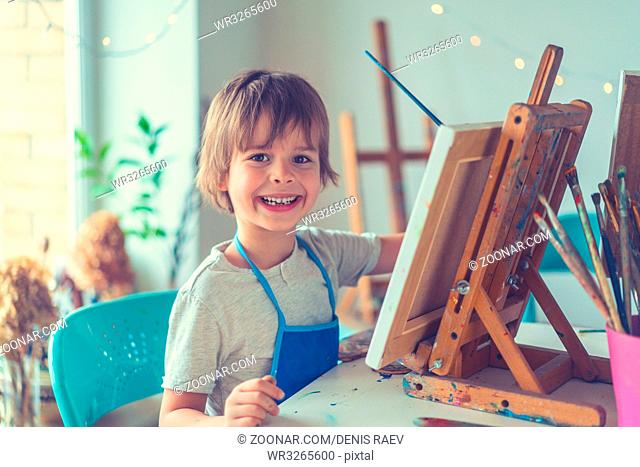 Smiling boy with an easel in studio