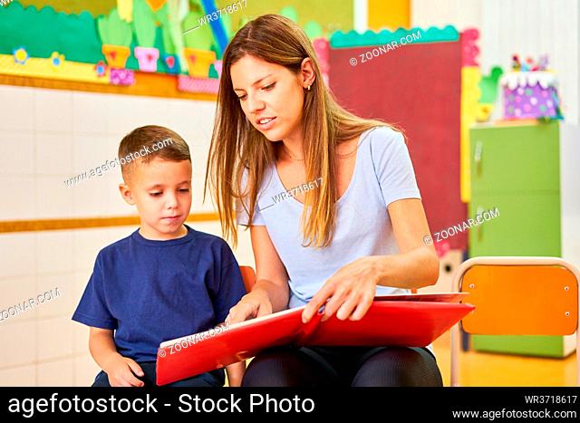 Kindergärtnerin oder Tagesmutter beim Buch vorlesen für ein Kind im Kindergarten oder Hort