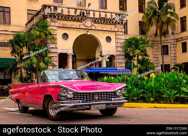 Havana, Cuba on January 13, 2016: A red oldtimer drives in front of Havanas infamous Hotel national which retains the charm of the Golden 20s - Havana