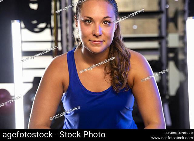 Straight on portrait of a young woman looking into camera after a workout