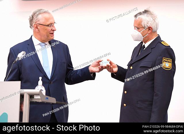 26 March 2021, Bavaria, Roding: Bavarian Minister of the Interior Joachim Herrmann (l, CSU) presents the State Police Chief Wilhelm Schmidbauer with his new...
