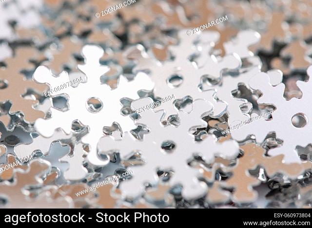 Christmas decoration of silver confetti snow flake against white background with nice boke. Close up confetti with shallow DOF