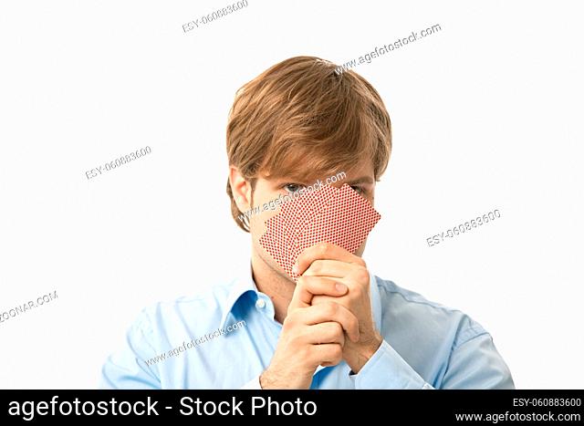 Young man holding playing cards in hand, looking over it. Isolated on white
