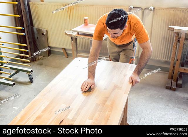 Carpenter polishing and varnishing a table in his workshop