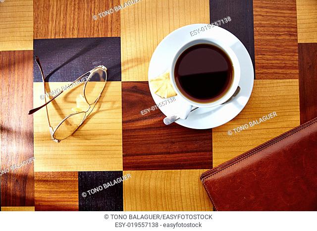 Coffee cup with glasses and leather folder on table retro vintage