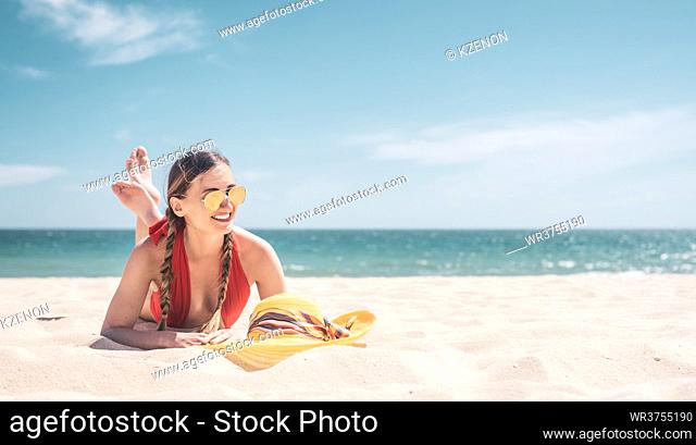Woman enjoying her vacation by the sea tanning on the sand beach