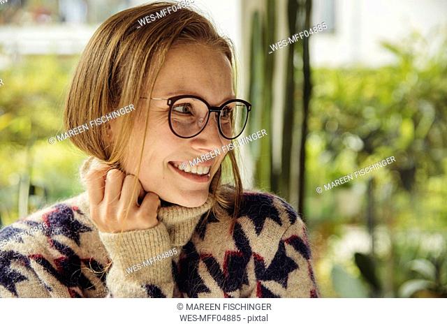 Portrait of smiling young woman with glasses wearing fluffy sweater looking sideways