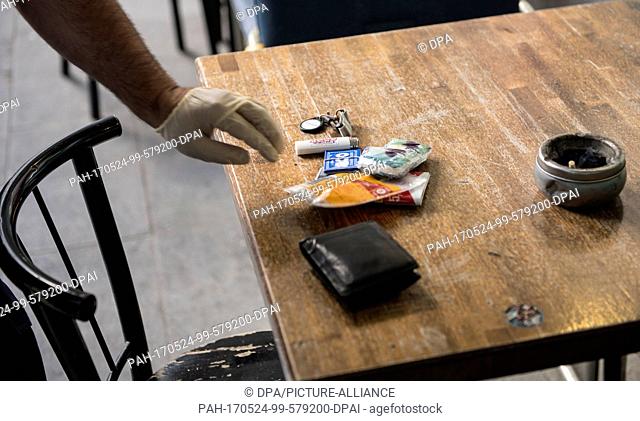 A police officer places objects from the pockets of a suspected drug dealer on a table during a search in the borough of Kreuzberg in Berlin, Germany