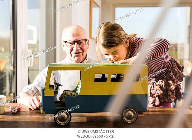 Grandfather and granddaughter assembling toy bus