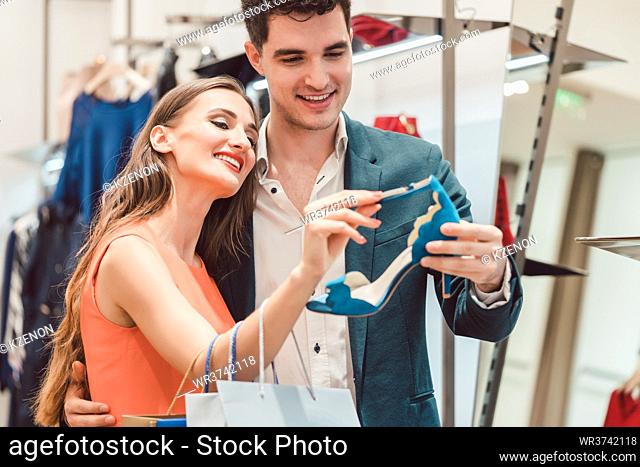 Woman with her man looking at blue shoes in store wanting them badly