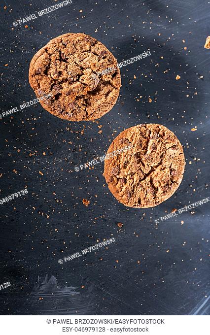 Group of chocolate cookies with crumbles flying over the black background. Close up