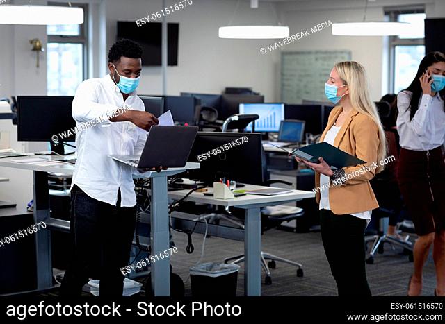 Businessman and businesswoman wearing face masks working at modern office