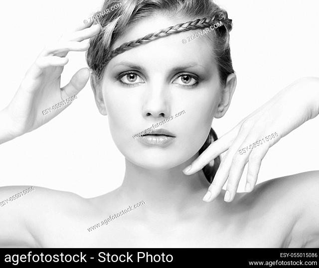 Black and white portrait in high key tone of beautiful young dark blonde woman with creative braid hairdo posing on gray