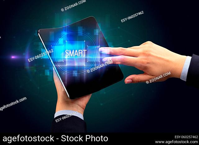 Businessman holding a foldable smartphone with SMART inscription, new technology concept
