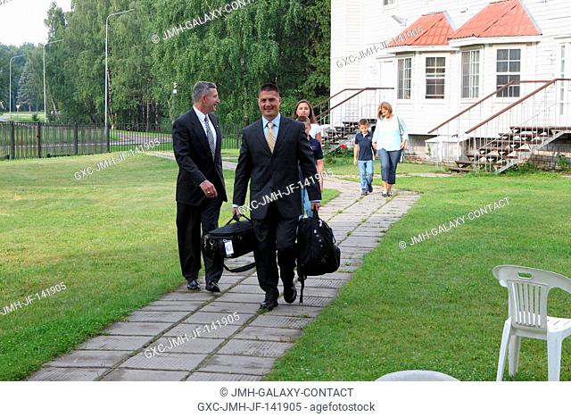 Toting his bags and with his family behind him, Expedition 4445 Flight Engineer Kjell Lindgren of NASA departs his residence at the Gagarin Cosmonaut Training...