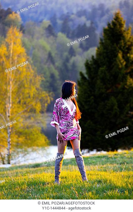 Attractive woman is posing on a meadow watching sunset