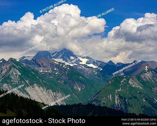 24 July 2021, Austria, Heiligenblut: The snow-covered summit of the Großglockner shines between clouds. The Großglockner is 3