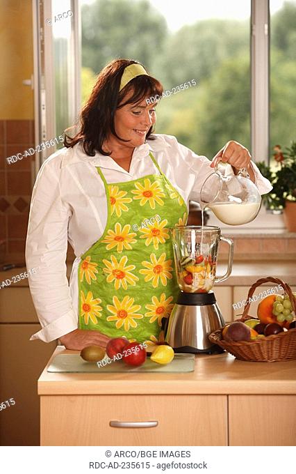 Woman pouring milk to fruits in blender / blitzing, adding, fruit basket, hairband