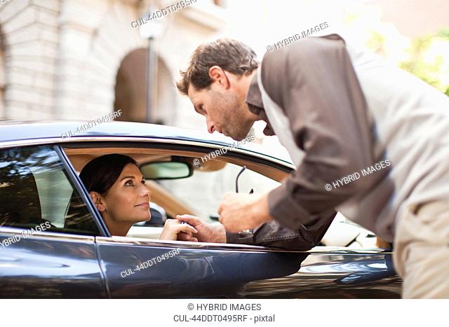 Man talking to woman through car window