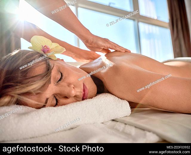Hand of mature woman giving back massage to senior woman on sunny day
