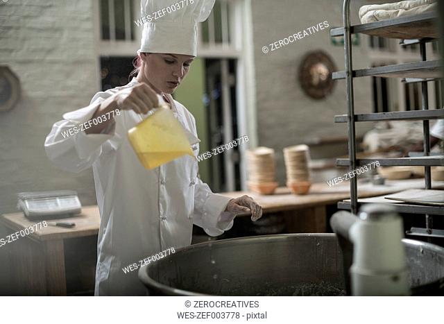 Female baker pouring ingredient into mixer