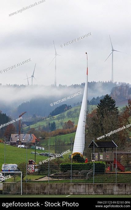 23 November 2023, Baden-Württemberg, Biberach: A wind turbine blade is mounted on a so-called self-propelled transporter and is being transported through the...