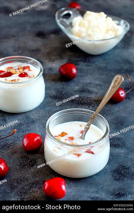 Fermented yogurt kefir in small bottles with cherries and walnuts close up