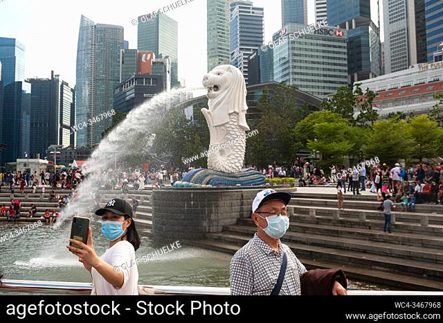 Singapore, Republic of Singapore, Asia - Tourists cover their faces with surgical masks at the Merlion Park in Marina Bay